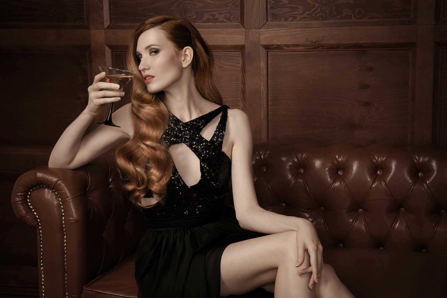 Red Headed Woman Sitting on Leather Couch with a Martini